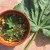 Picture of cooked mallow leaf with chickpeas in a bowl, with a large mallow leaf on the side